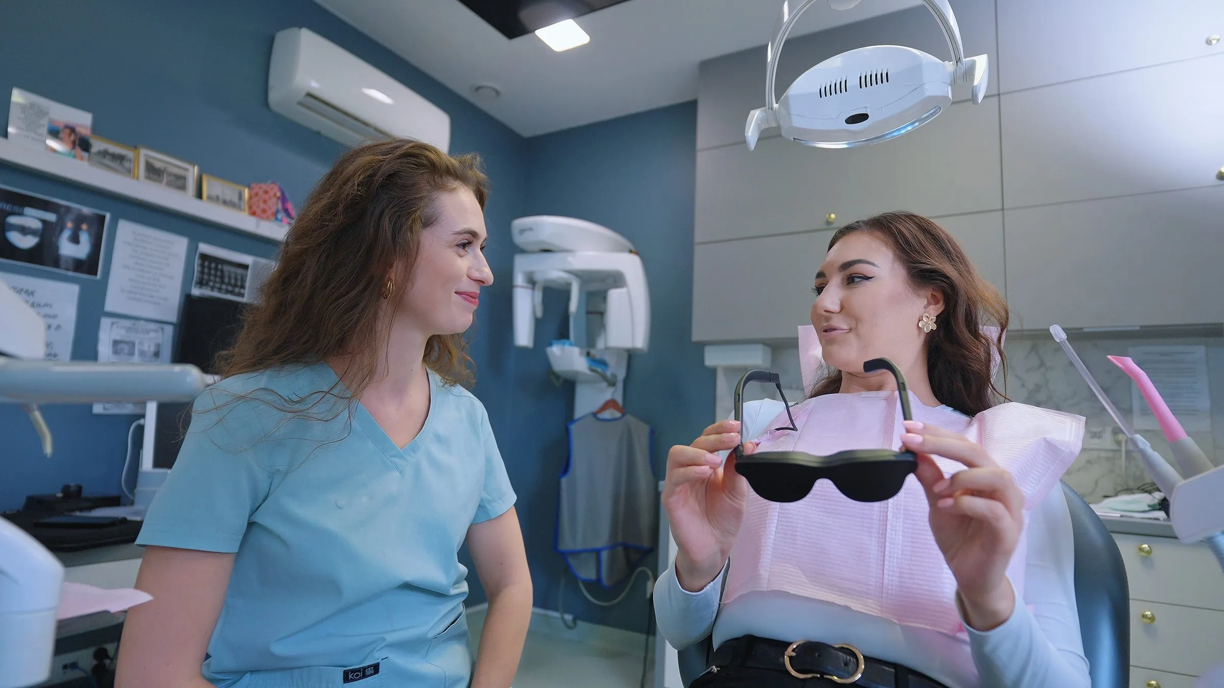 Lekarka rozmawia z pacjentką trzymającą okulary Dental Glasses
